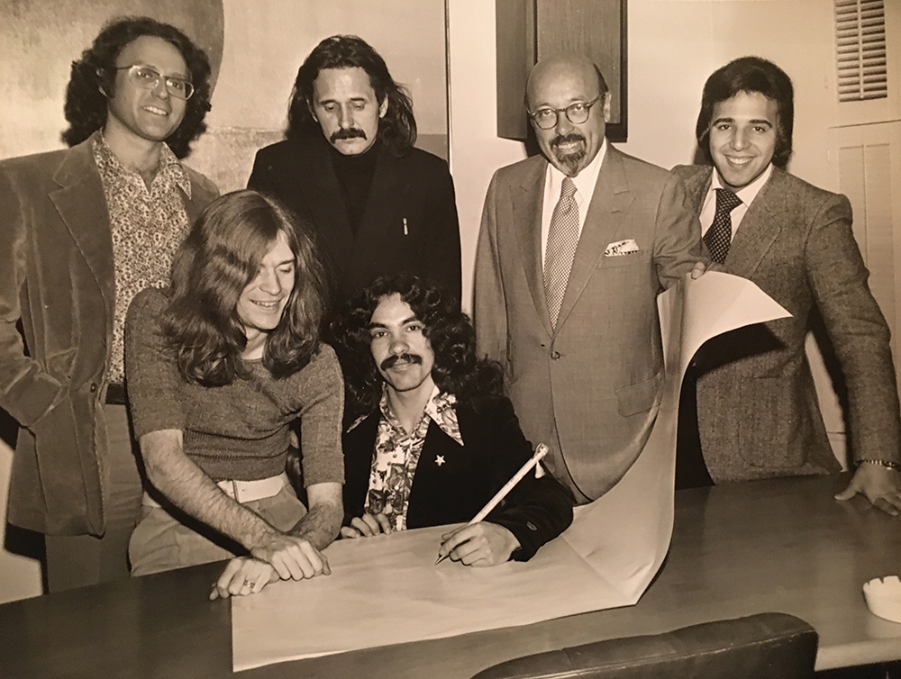 The duo signed a contract with Atlantic Records in 1972. Behind them from left, A&R executive Mark Meyerson, producer Earl McGrath, Atlantic Records founder and president Ahmet Ertegun, and manager Tommy Mottola. Courtesy of John Oates