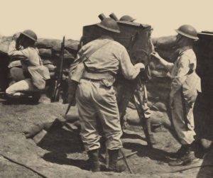 Members of a gun crew operate the M-5 gun director. The soldiers on either side of the box track the target through the telescopes while the corporal on the right estimates and enters the range.