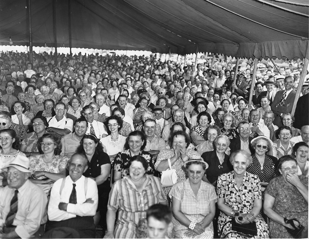 A delighted crowd laughs at the Pennsylvania Dutch standup comedy routine of Professor Schnitzel (Theodore Rickenbach).
