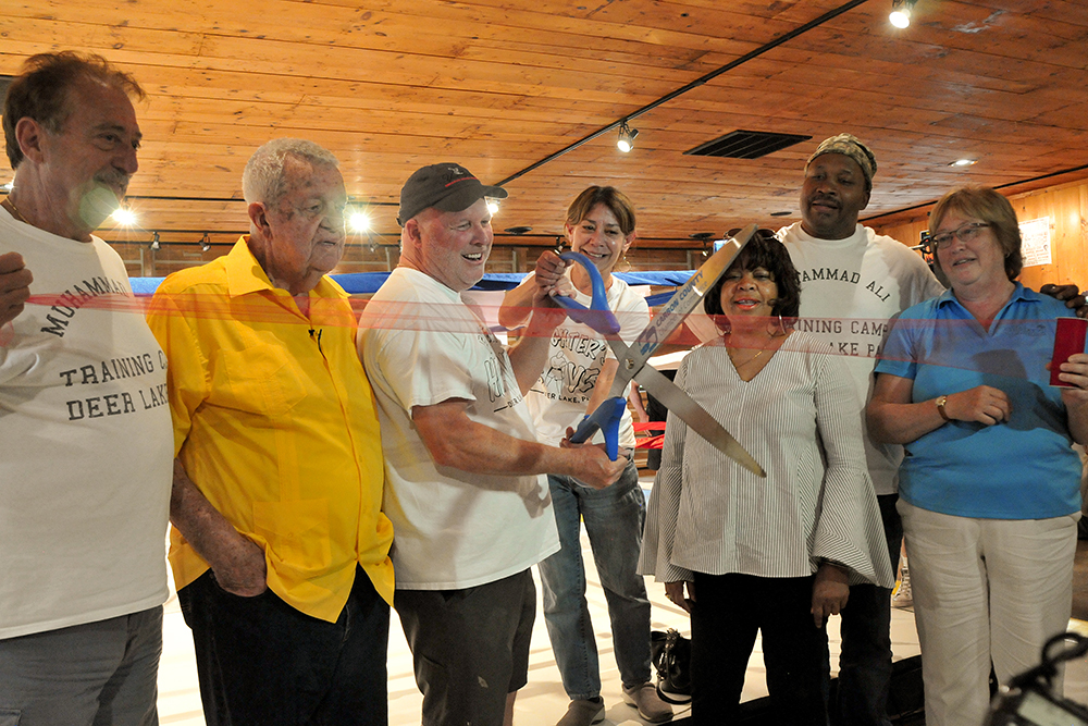 Mike Madden, center, cuts the ribbon at the official grand opening of Fighter’s Heaven on June 1, 2019. Special guests that day included Gene Kilroy, second from left, a prominent member of Ali’s inner circle who was instrumental in Ali’s choosing to build the camp at Deer Lake and former heavyweight champ Tim Witherspoon, second from right, who got his start at the camp as a sparring partner to Ali. Also pictured are, first from left, camp manager and media relations director Sam Matta and, from Madden’s right, his fiancee Susie Lorenzi, Philadelphia boxing judge Lynne Carter, and director of economic development for Carbon Chamber & Economic Development Corp. Kathy Henderson. Photo, ©Jeff Julian