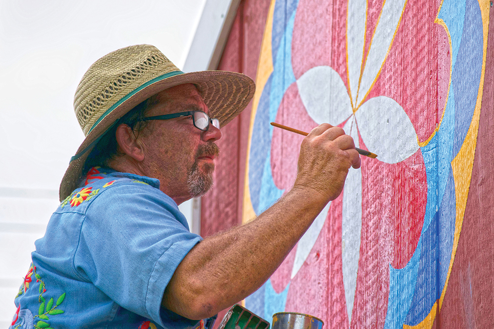 Barn star painter Eric Claypoole of Lenhartsville, Berks County, deftly stripes the edge of an elaborate rosette pattern produced for the Kutztown Folk Festival in 2018 to promote the region’s living traditions. Photo, Naomi Pauley, Pennsylvania German Cultural Heritage Center, Kutztown University