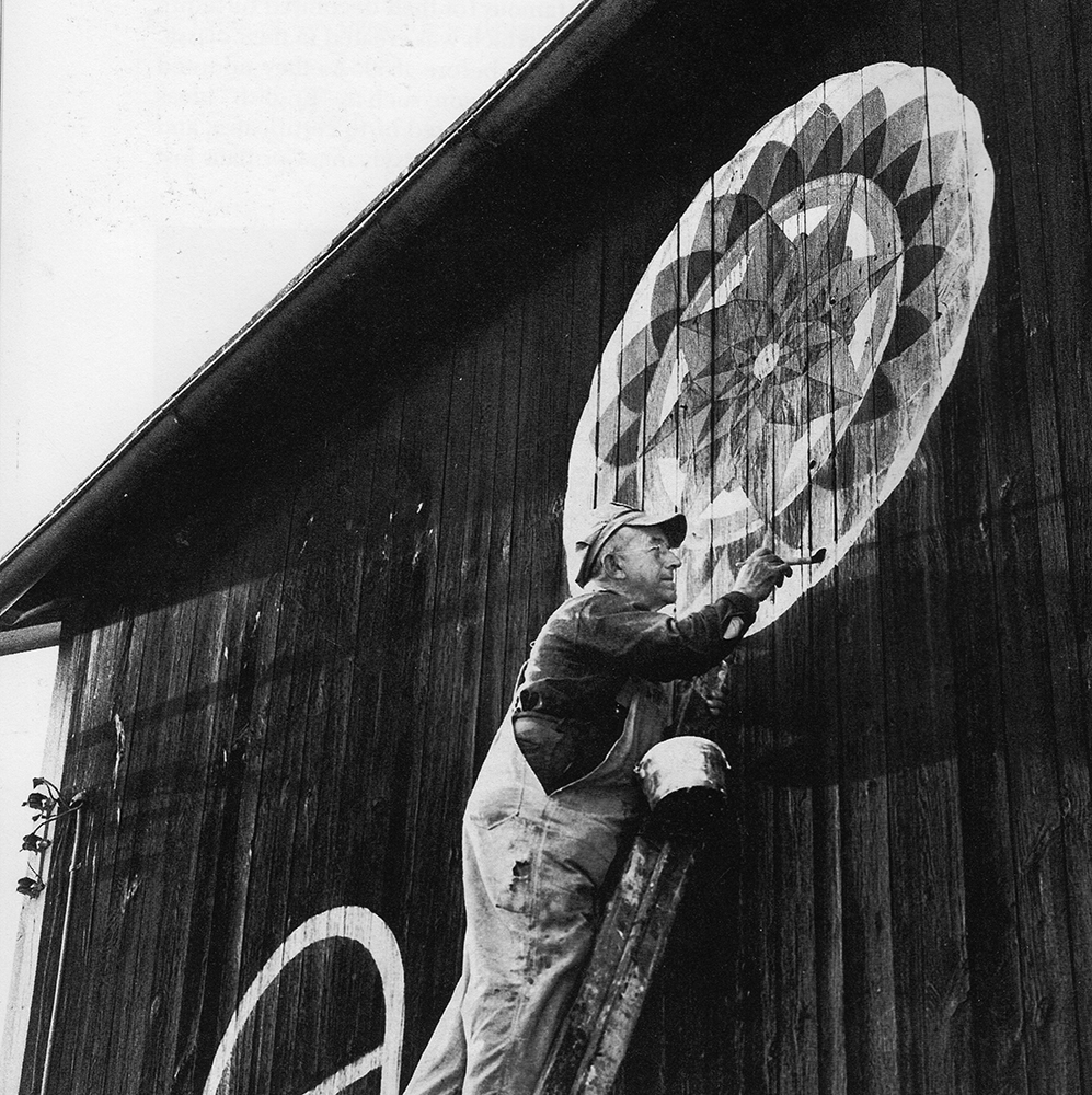 Venerated barn star painter Milton J. Hill of Virginville, Berks County, paints one of his classic, elaborate signature stars on the barn at his family farm. Hill began painting barn stars decades before the term “hex sign” was introduced through tourism. Pennsylvania Folklife Society
