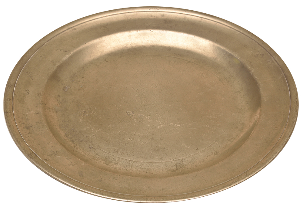 Throughout the 1760s more than 300 tons of British pewter goods, such as this offering plate manufactured by Bush & Perkins in Bristol, were exported annually to the American colonies. British law taxed unworked pewter and forbade the import of tin, pewter’s primary component, meaning colonial pewterers were restricted to repairing, refashioning or melting down English pewter to create new objects. The State Museum of Pennsylvania