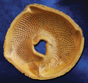 An early 19th-century redware pottery mold made in Berks County was carefully formed to produce a shallow, circular, fish-shaped cake or gelatin to celebrate the new year. This tradition was once common in the Rhine River Valley in the German Palatinate, as well as Alsace, France, where the moule à poisson pour gâteaux de nouvel-an (fish mold for New Year’s cake) is still widely used. Pennsylvania German Cultural Heritage Center, Kutztown University