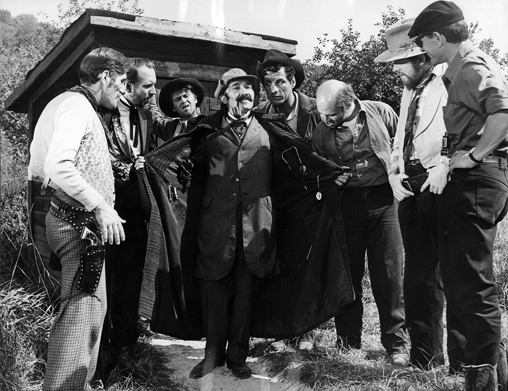 Sherlock Holmes pulls one over on the residents of Hope Canyon in this scene from The Double-Barrelled Detective Story. The characters, from left, are Wells Fargo Ferguson (Paul Benedict), Judge Parker (Ray Reinhardt), Shadbelly Higgins (Louis Waldon), Sherlock Holmes (Jerome Raphael), Sheriff Fairfax (Robert Winston), Byrne Piven (Bill Stone), and H.S. Stevens (Severn Darden). Director Adolfas Mekas is on the far right. Karl Bissinger Papers, University of Delaware Library