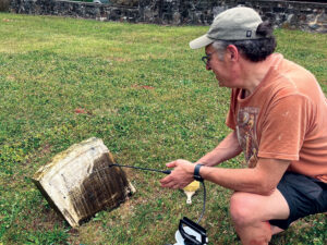 A member of the Lower Makefield Township Historical Commission carefully cleans a grave marker at Slate Hill Cemetery. Lower Makefield Township Historical Commission
