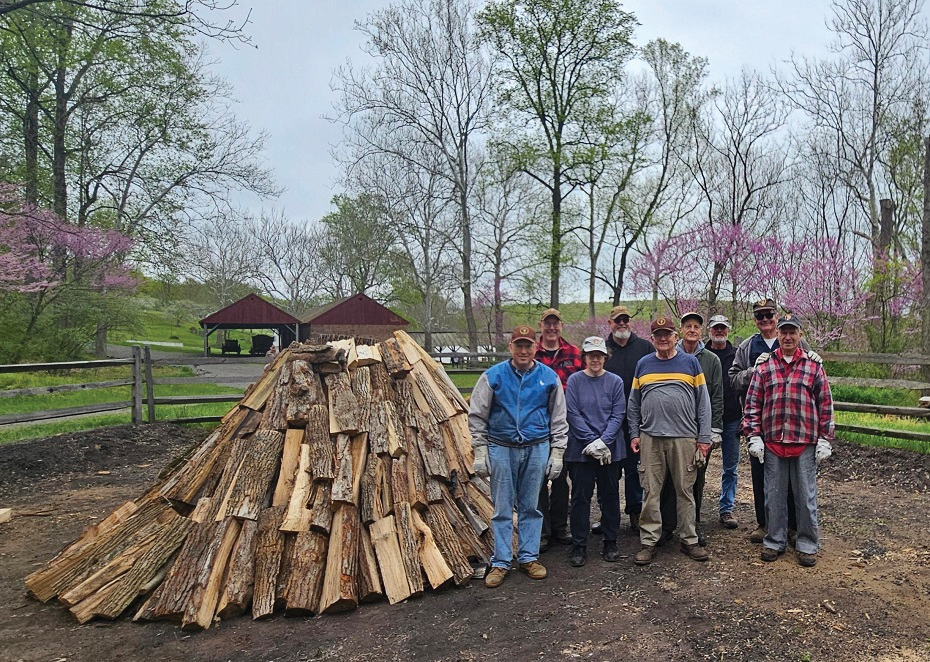 The three hard chores of charcoal making are building the wood pile, dusting the pile (putting leaves and earth on the sides), and raking out the charcoal at the end (if you don’t count cutting and splitting the wood). These chores require a small group of volunteers. Once the pile is burning, only two volunteers are needed, but they must be there 24 hours a day. Photo, Suzanne Reisser