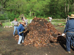 Leaves and then dirt are used to cover the wood pile before igniting it. Photo, Thomas J. Straka